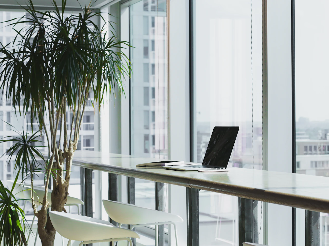 A light-filled workspace with a laptop and notebook beside the window.